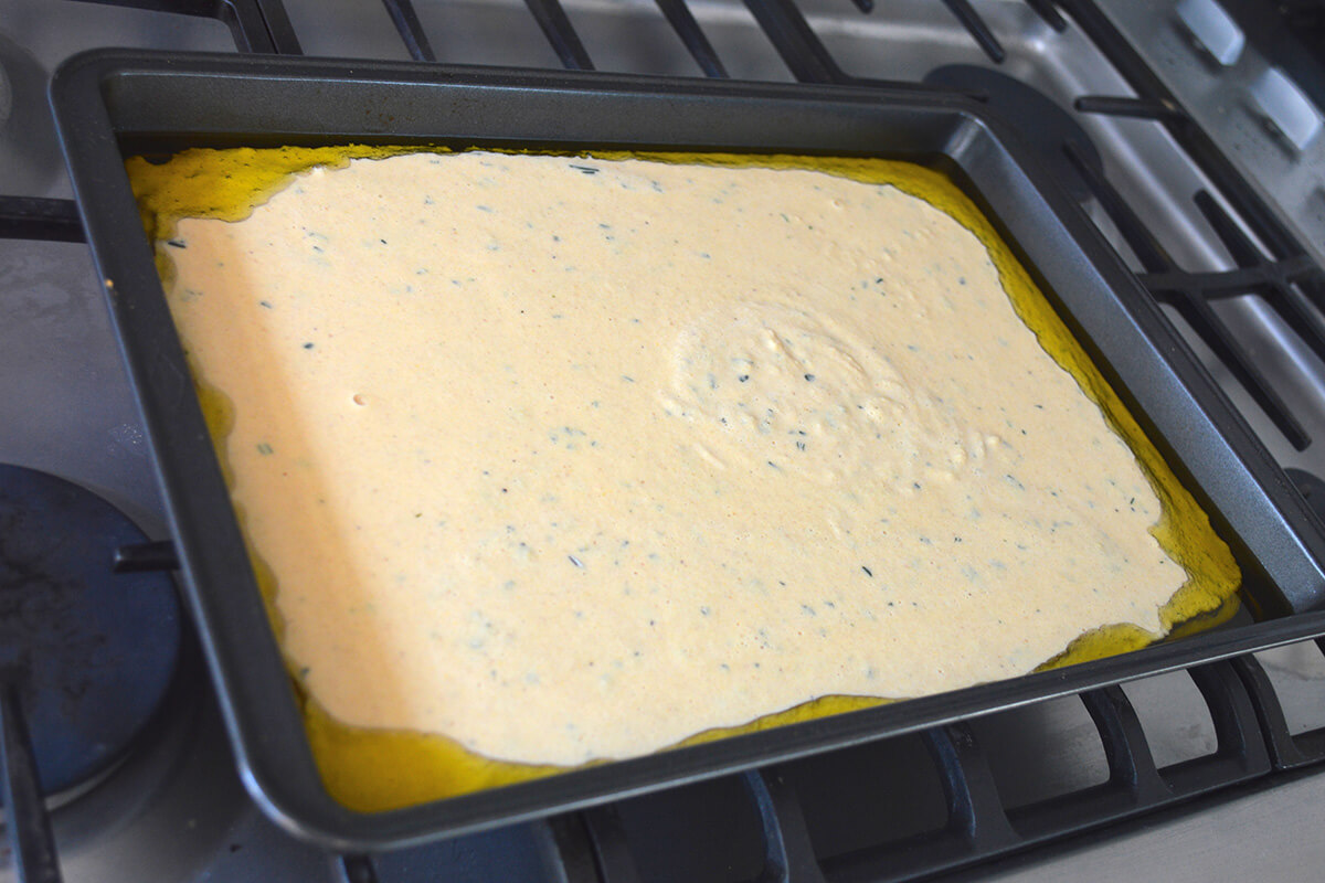A baking tray with uncooked farinata batter