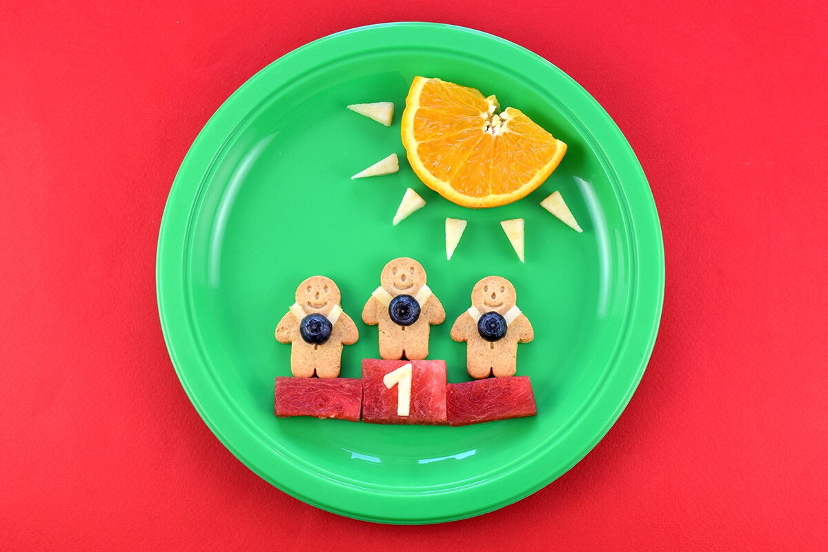 An apple cut into the shape of the number 1 is placed on the watermelon in the centre to complete the Winning Gingerbread Men Fun Plate