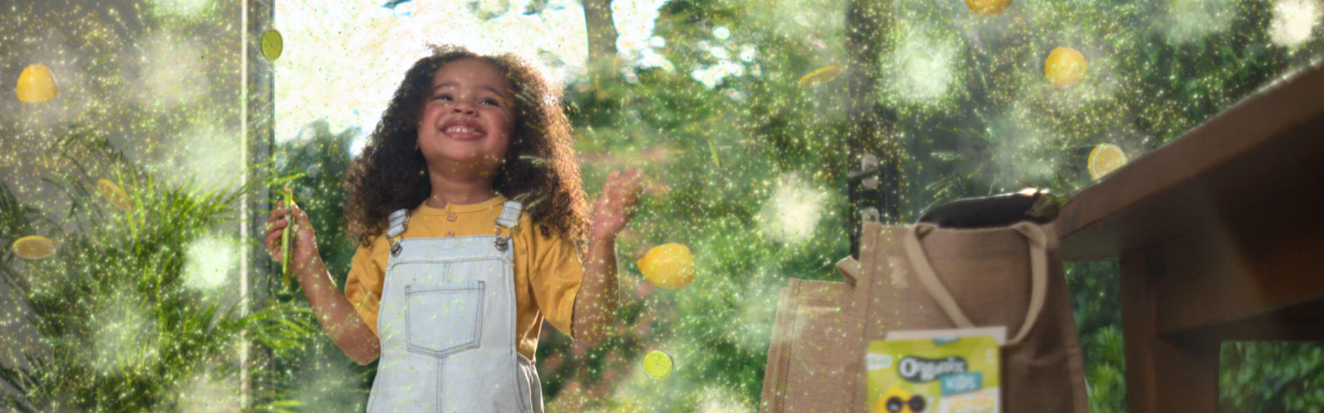 A toddler eating Organix snacks with some animated lemons, limes and sparkles around her