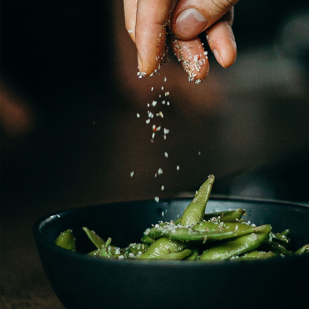 Salt sprinkled over a bowl containing edamame beans