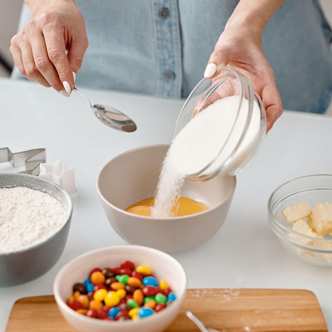 table with small bowls containing baking ingredients, one of them is sugar