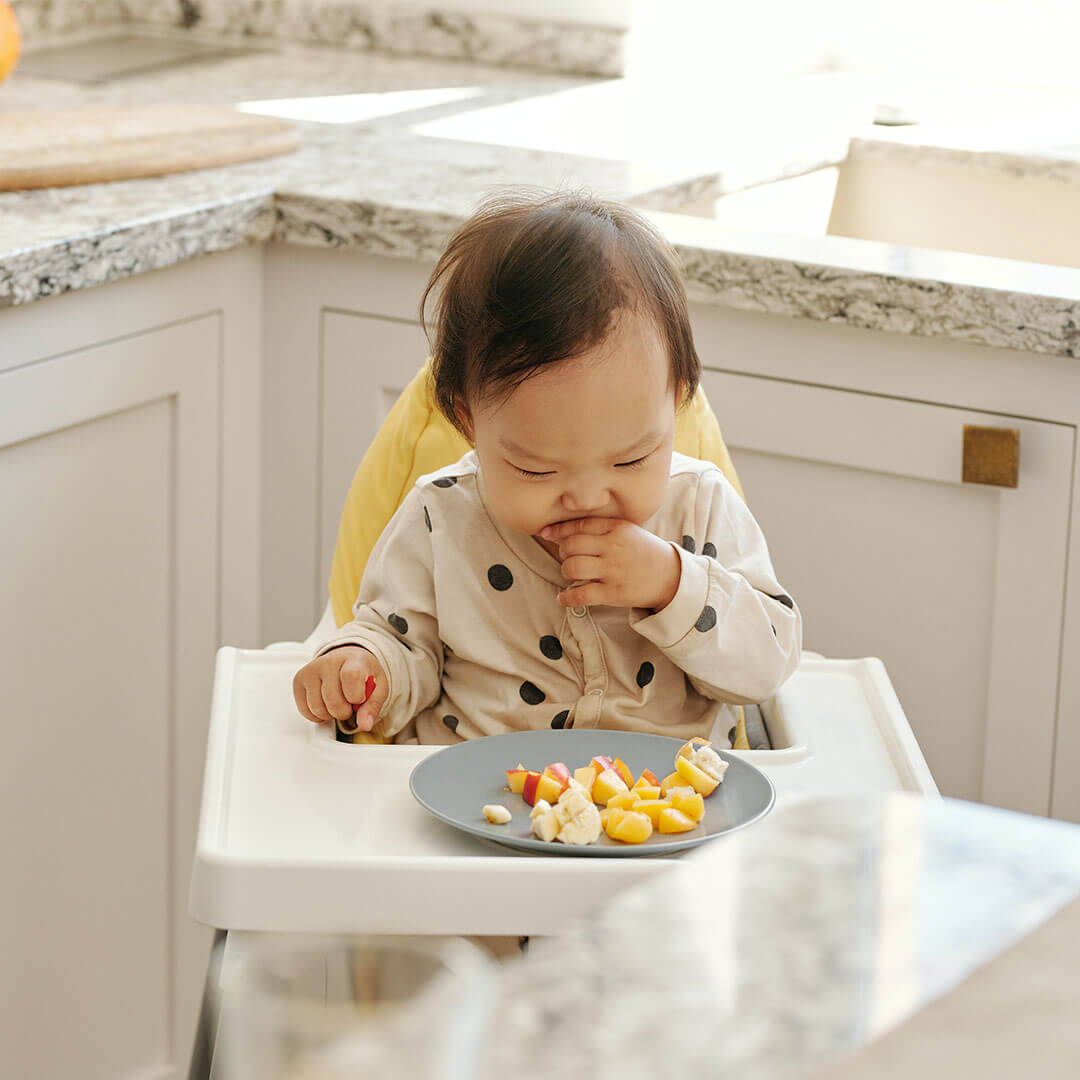 A baby sitting on a high chair and eating