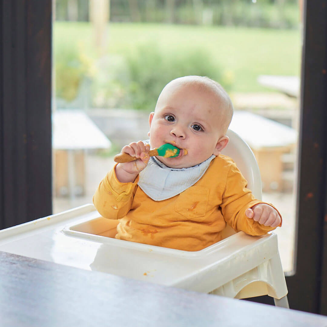 A baby sitting on a high chair and eating