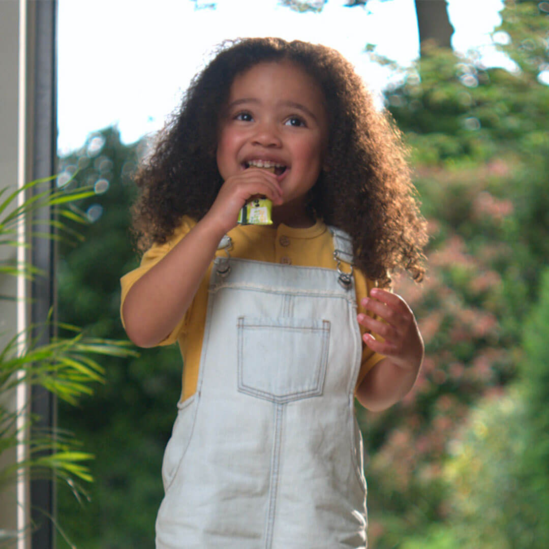 A toddler smiling and eating a snack