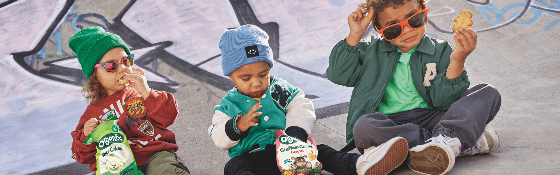 Three boy toddlers eating Organix snacks in the skatepark